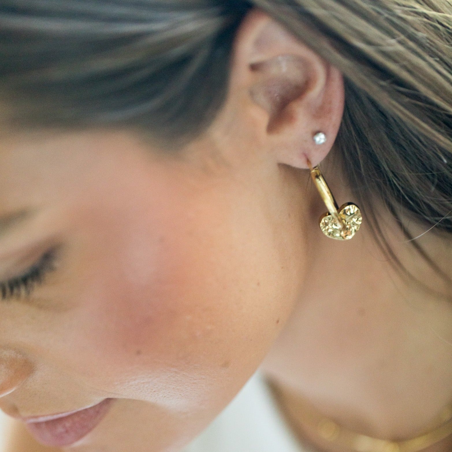 gold hammered heart on a gold hoop earring left ear