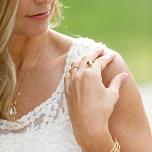 gold ring with ball on left index finger