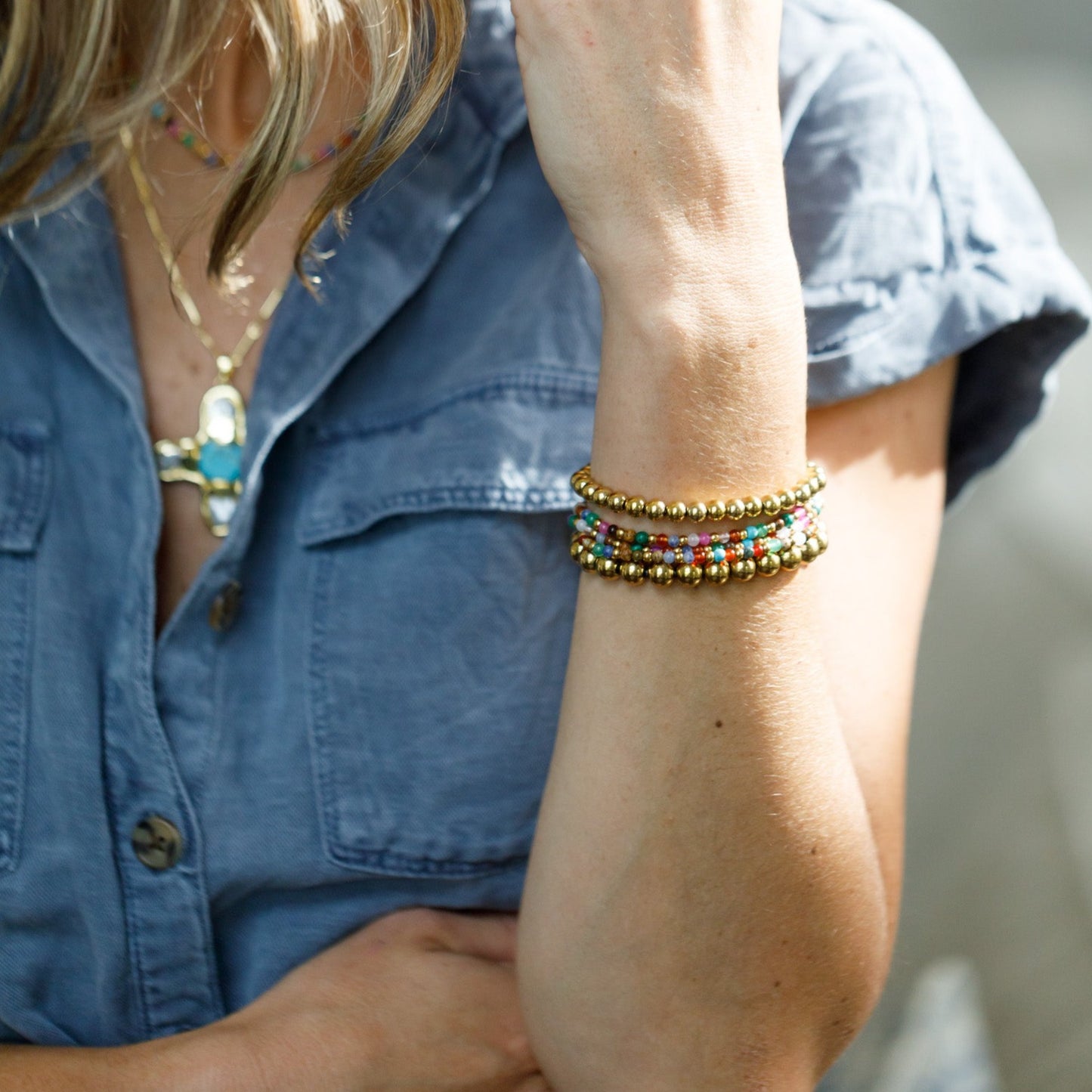 natural stone bracelet layered with gold beads on left wrist 