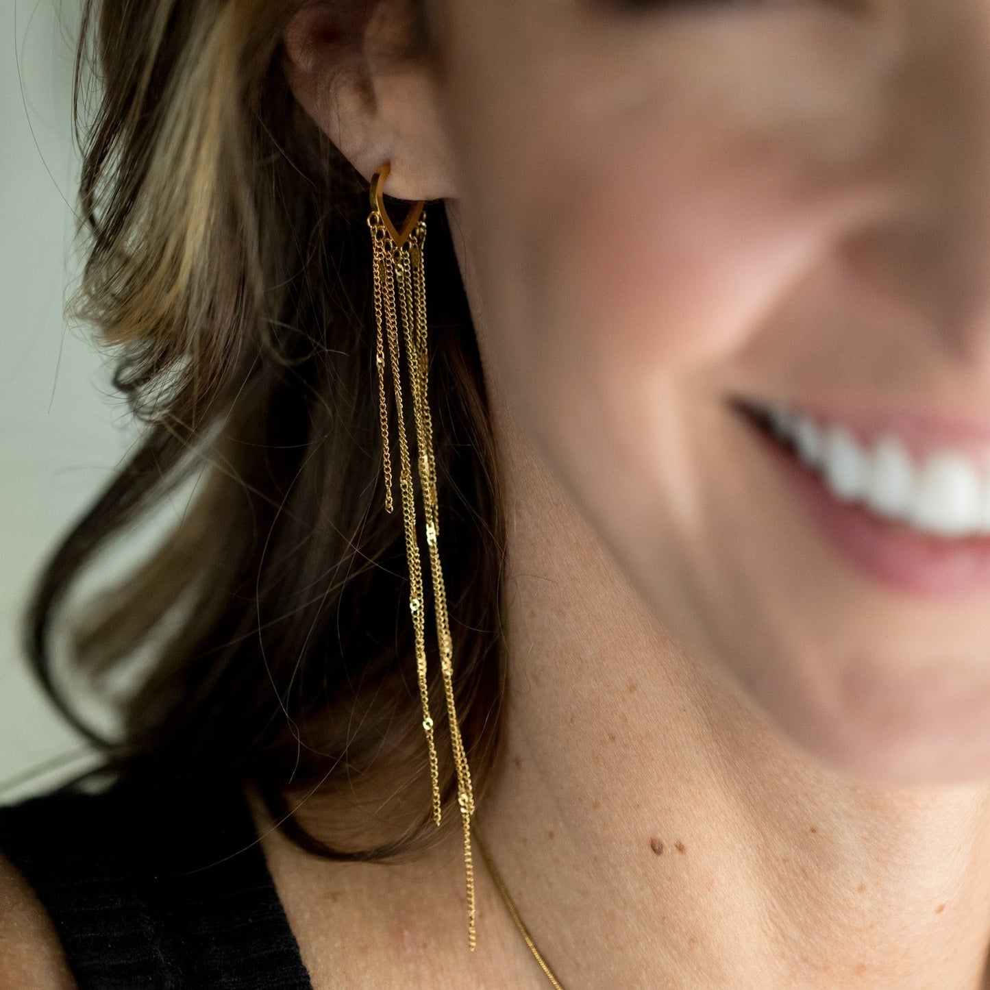 gold heart earrings with hanging strands right ear