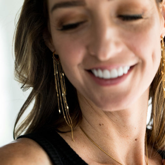 gold heart with hanging strands earrings on both ears